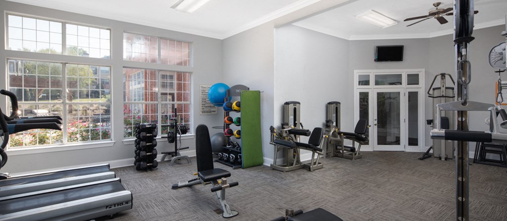 a gym with weights and cardio equipment in a room with windows