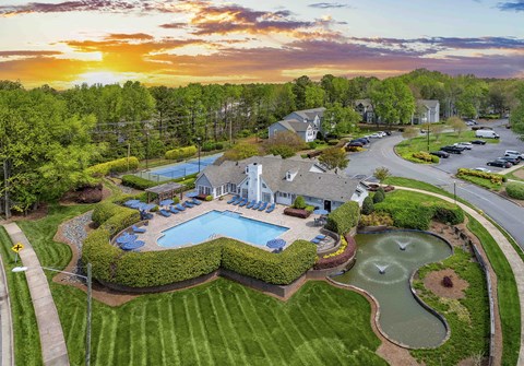 an aerial view of a pool and yard with a house and a sunset
