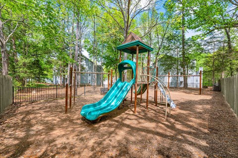 A playground with a green slide and a brown wooden structure.