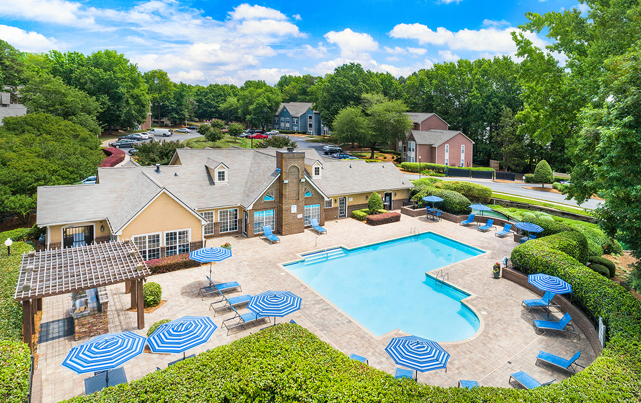 an aerial view of the resort style pool with blue and white umbrellas