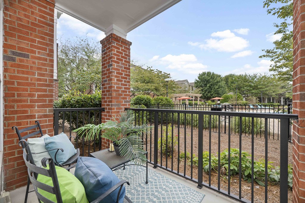 A patio with a black railing and a brick pillar.