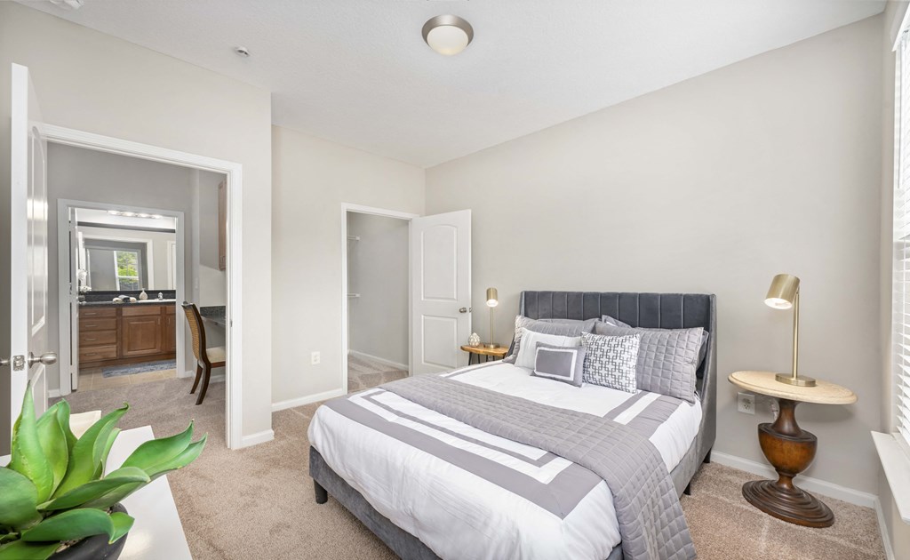 A bedroom with a large bed and a plant on the table.