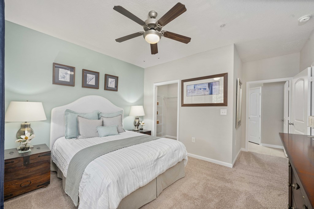 A bedroom with a bed, nightstands, and a ceiling fan.