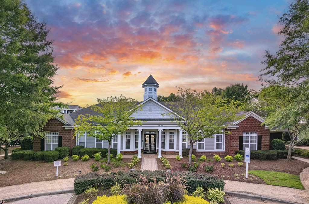 A house with a tower and a front yard with a bush.