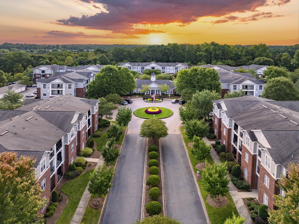 A sunset view of a residential area with apartment buildings and a central garden.