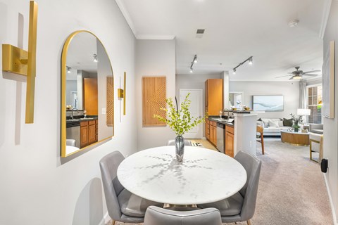 A modern dining room with a round marble table and grey chairs.