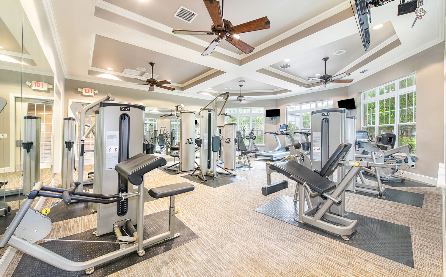 a gym with cardio equipment and ceiling fans