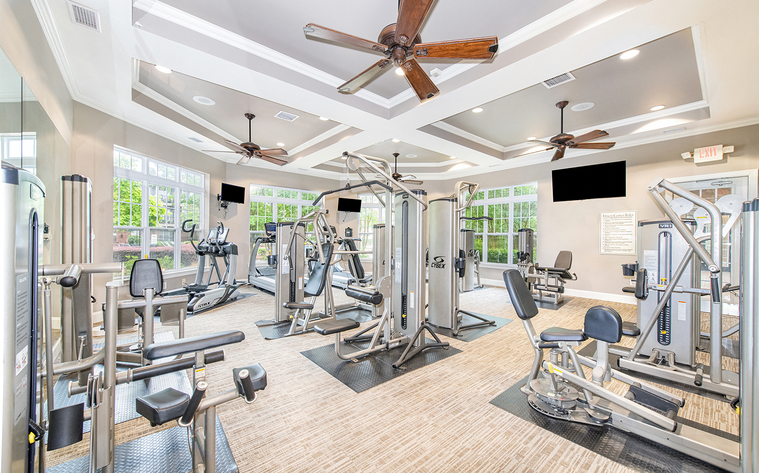 a gym with cardio machines and a ceiling fan