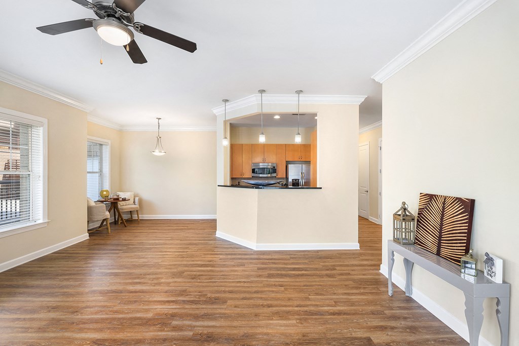 A spacious living room with a ceiling fan and hardwood floors.