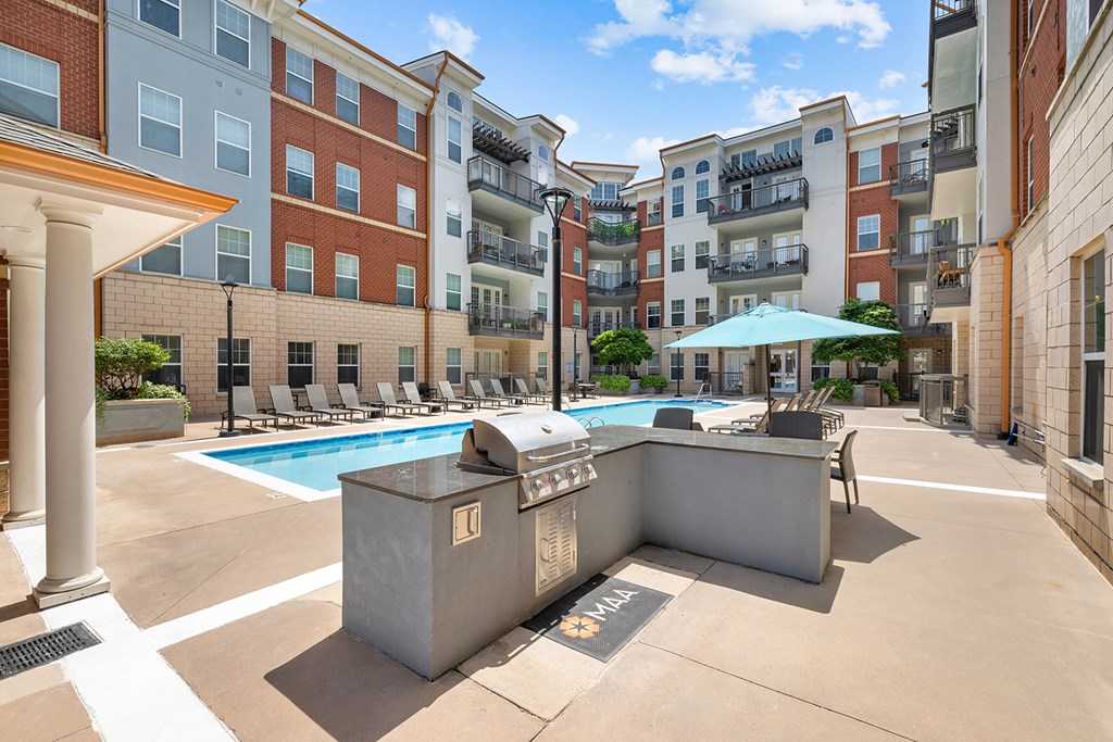 A pool with a hot tub and lounge chairs in front of apartment buildings.