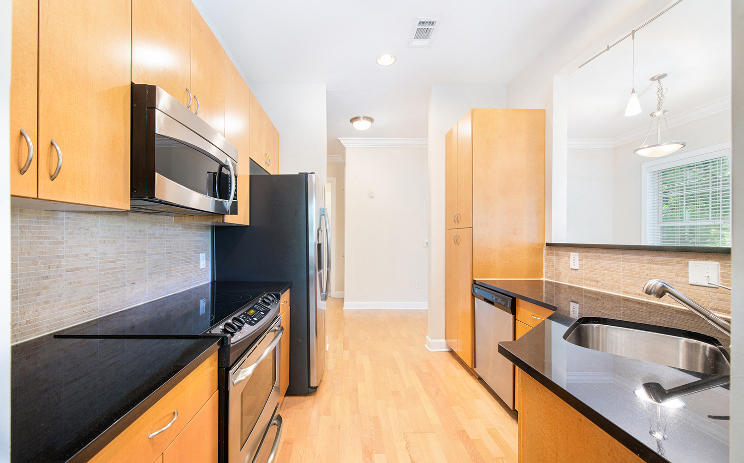 a kitchen with black counter tops and black appliances and wooden cabinets
