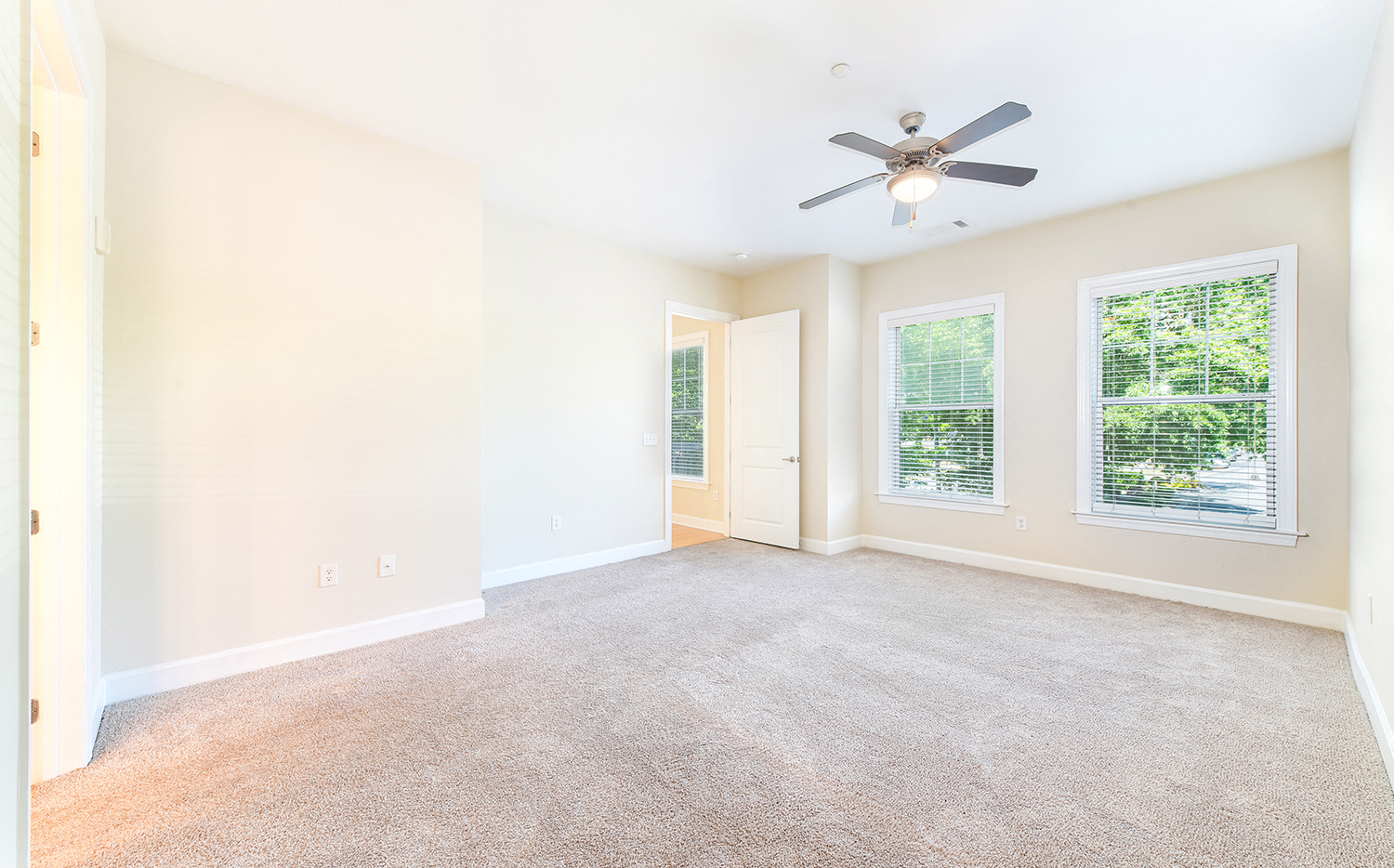 an empty living room with a ceiling fan and a window