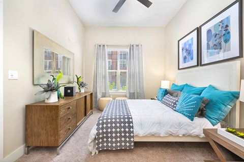 A bedroom with a bed, dresser, and ceiling fan.