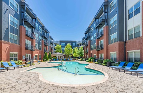A swimming pool in the middle of a courtyard surrounded by apartment buildings.