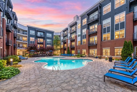 A swimming pool surrounded by a stone patio and blue lounge chairs.