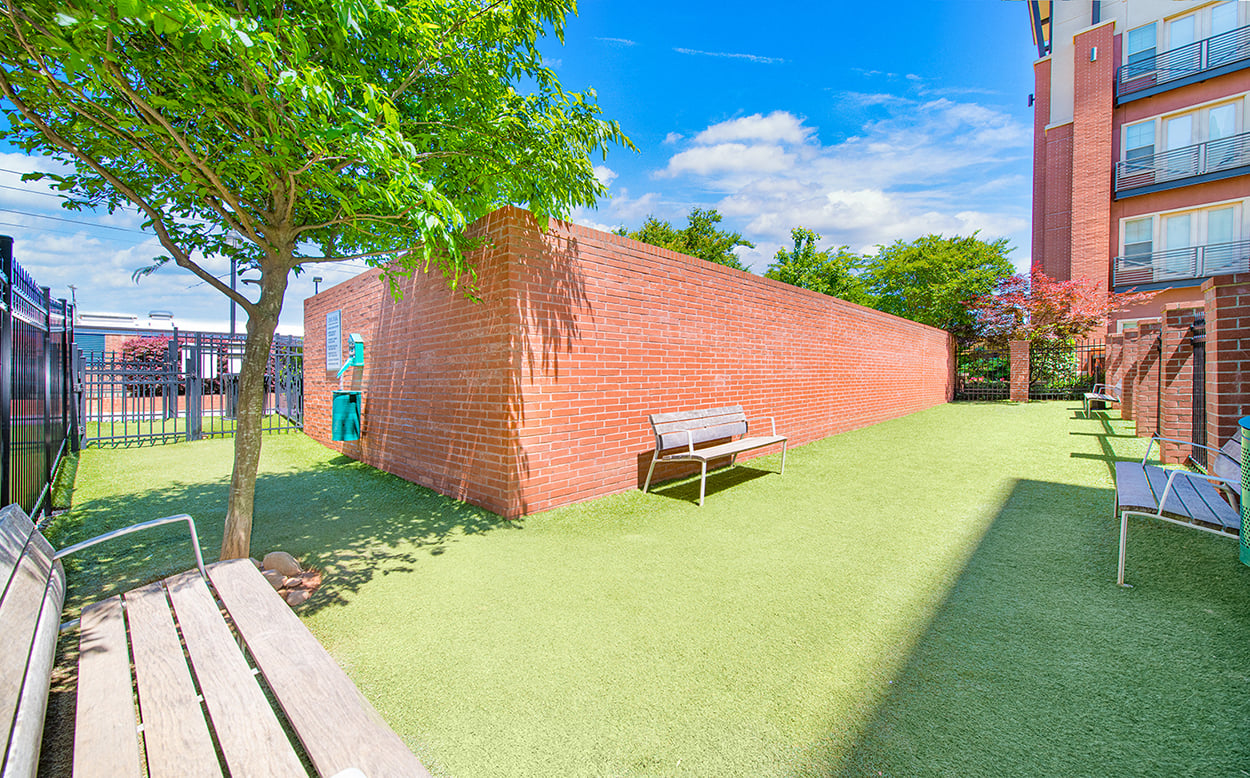 a yard with a bench and a brick wall