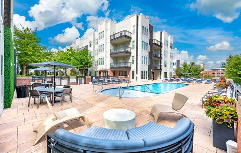 A sunny day at a poolside with a building in the background.