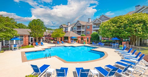A large swimming pool surrounded by blue lounge chairs.