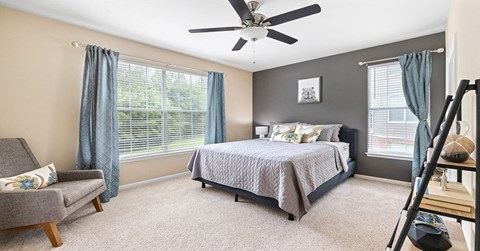 A bedroom with a bed, chair, and window.