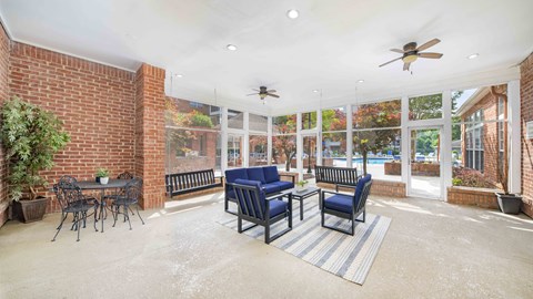 a living room with blue chairs and a brick wall and windows