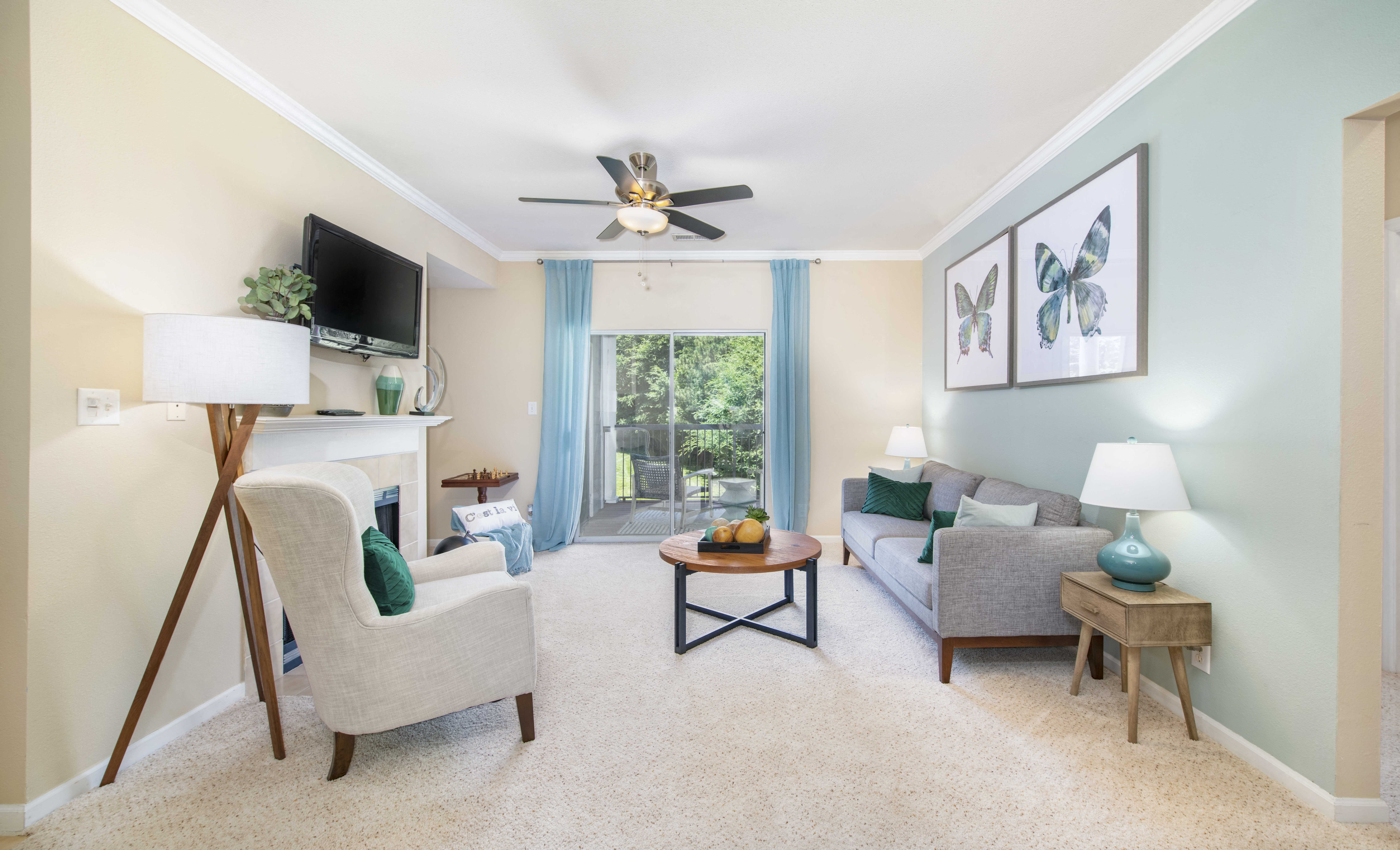 a living room with couches and a tv and a ceiling fan