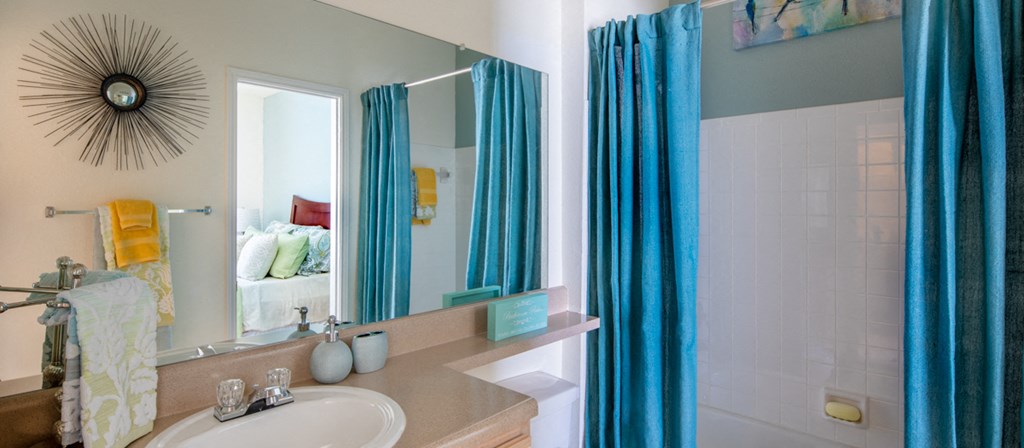 a bathroom with a white sink and blue curtains