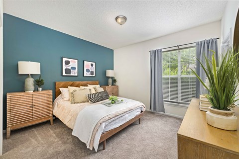 A bedroom with a bed, nightstands, and a plant.