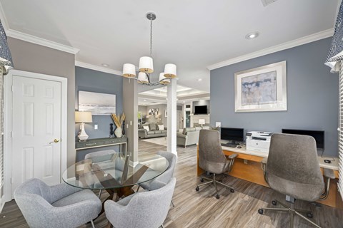 A modern home office with a glass table and grey chairs.