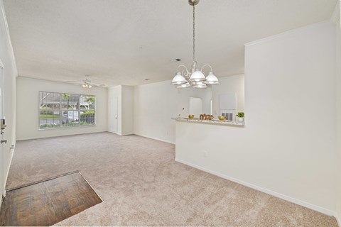 A room with a white ceiling and walls, a wooden floor, and a hanging light fixture.