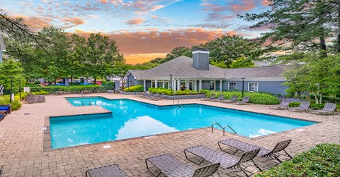A large outdoor swimming pool surrounded by lounge chairs and trees.