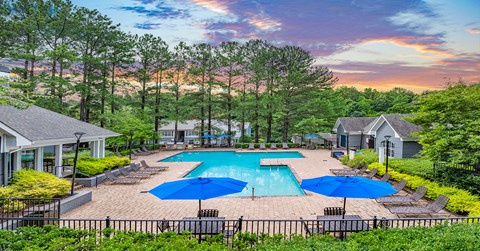 A beautiful outdoor swimming pool surrounded by trees and houses.