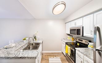 a renovated kitchen with granite counter tops and white cabinets