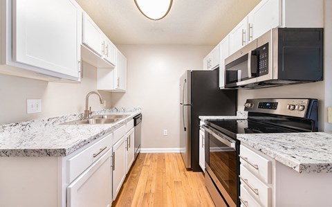 an empty kitchen with white cabinets and black appliances