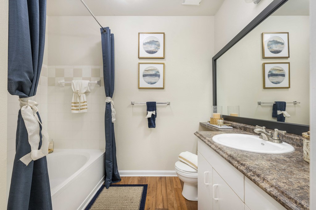 A bathroom with a white toilet, a white sink, a white bathtub, and a white towel hanging on the side of the tub.