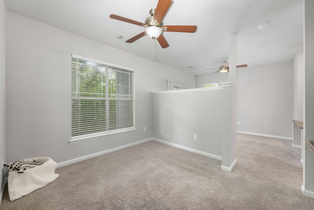 A room with a ceiling fan and a window with blinds.