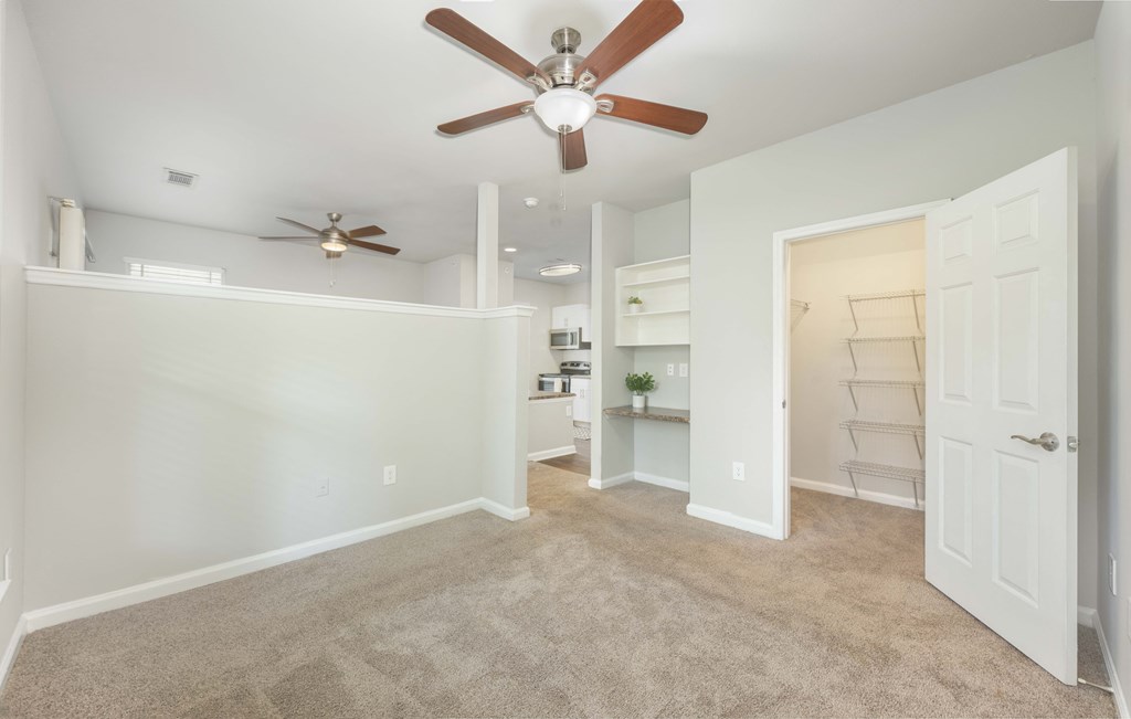 A room with a ceiling fan and a door leading to another room.