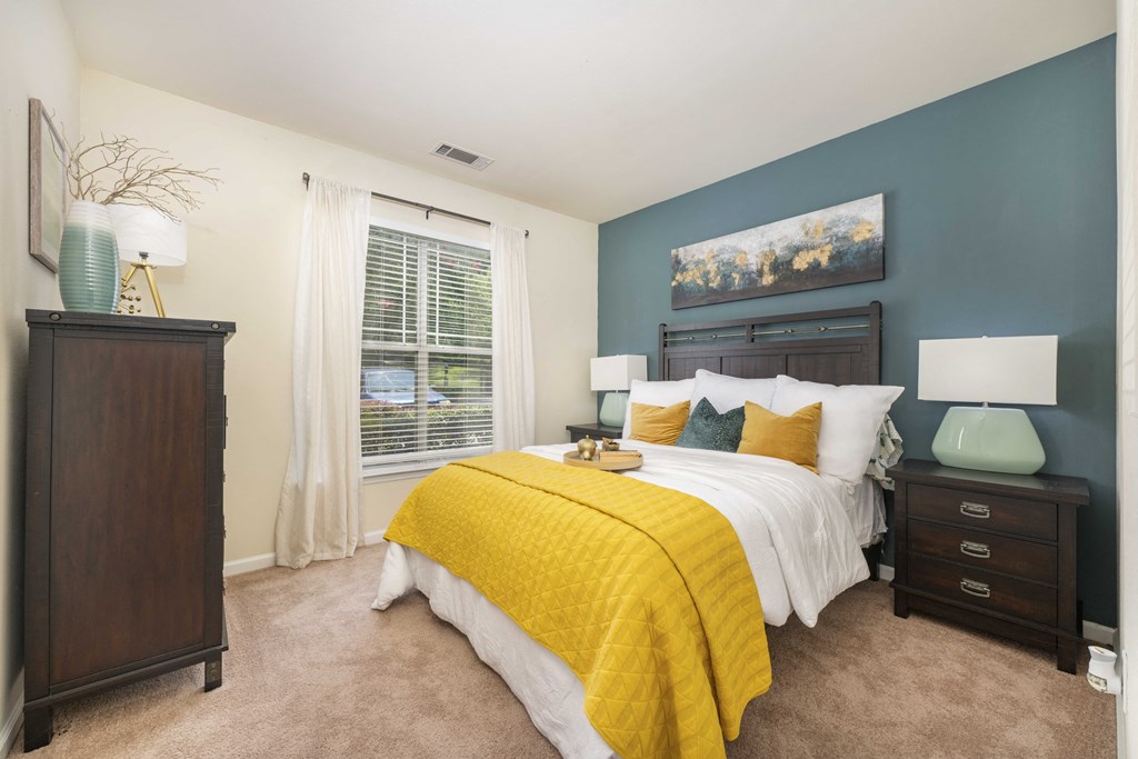 A bedroom with a bed, nightstand, and a painting on the wall.