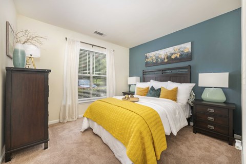 A bedroom with a bed, nightstand, and a painting on the wall.