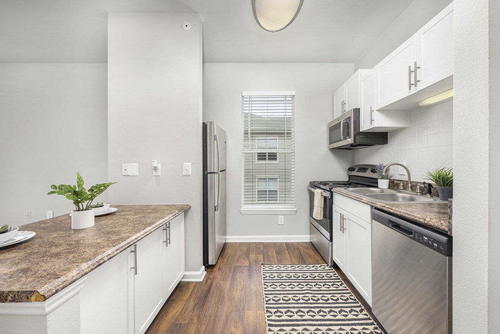 A kitchen with a refrigerator, oven, and sink.