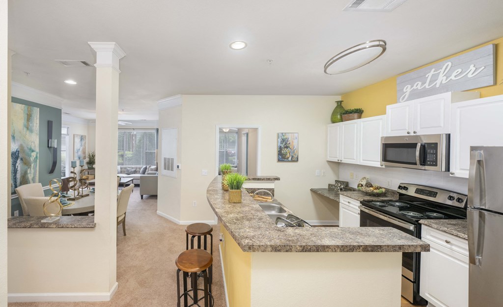 A kitchen with a bar stool in front of the counter.