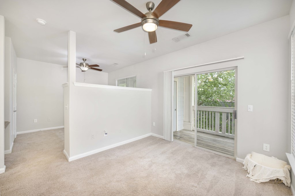 A room with a ceiling fan and a window with a view of trees.