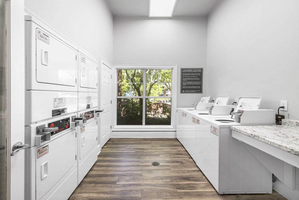 A kitchen with white appliances and a window showing trees outside.