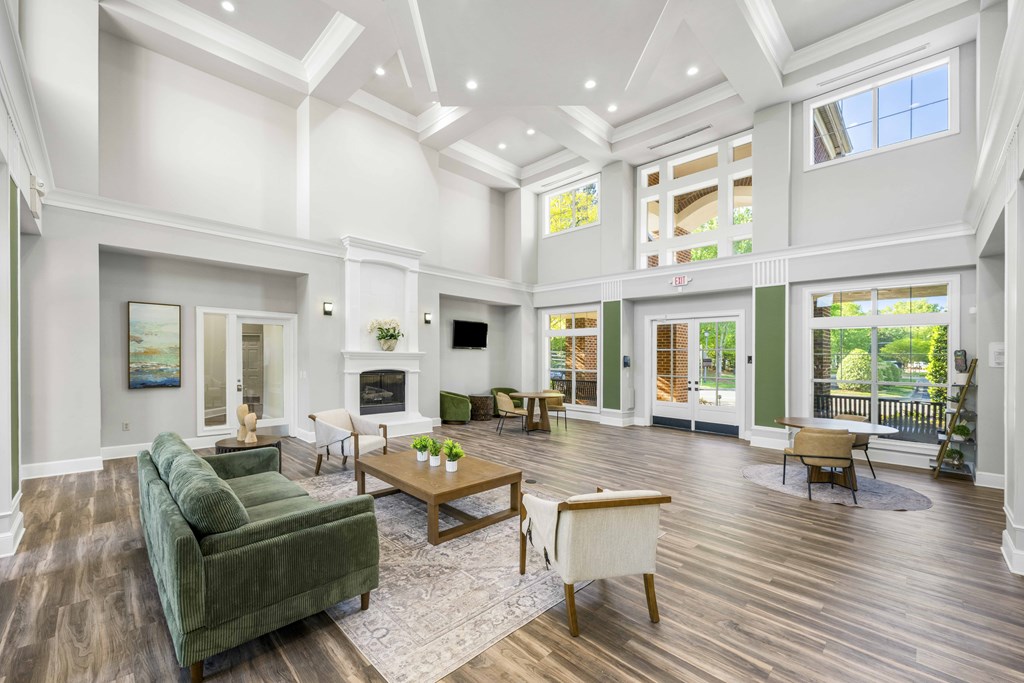 A large, well-lit living room with a green couch, wooden coffee table, and a fireplace.