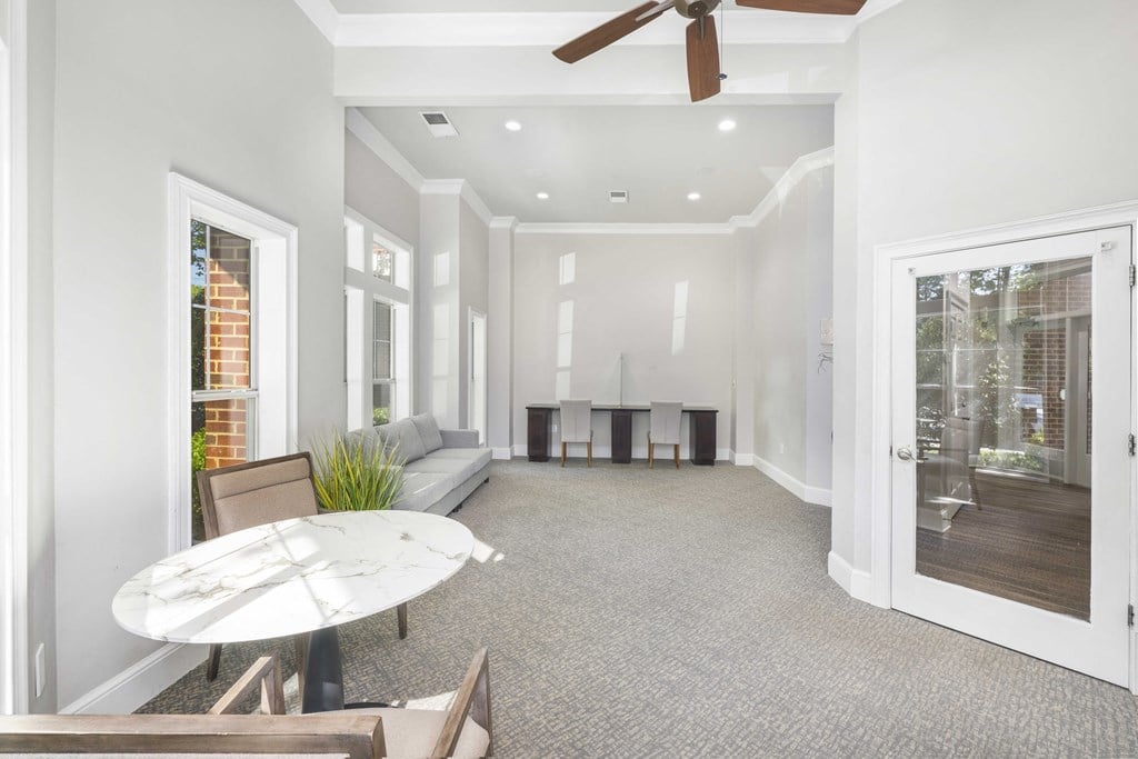 A spacious living room with a white ceiling fan and a white table.