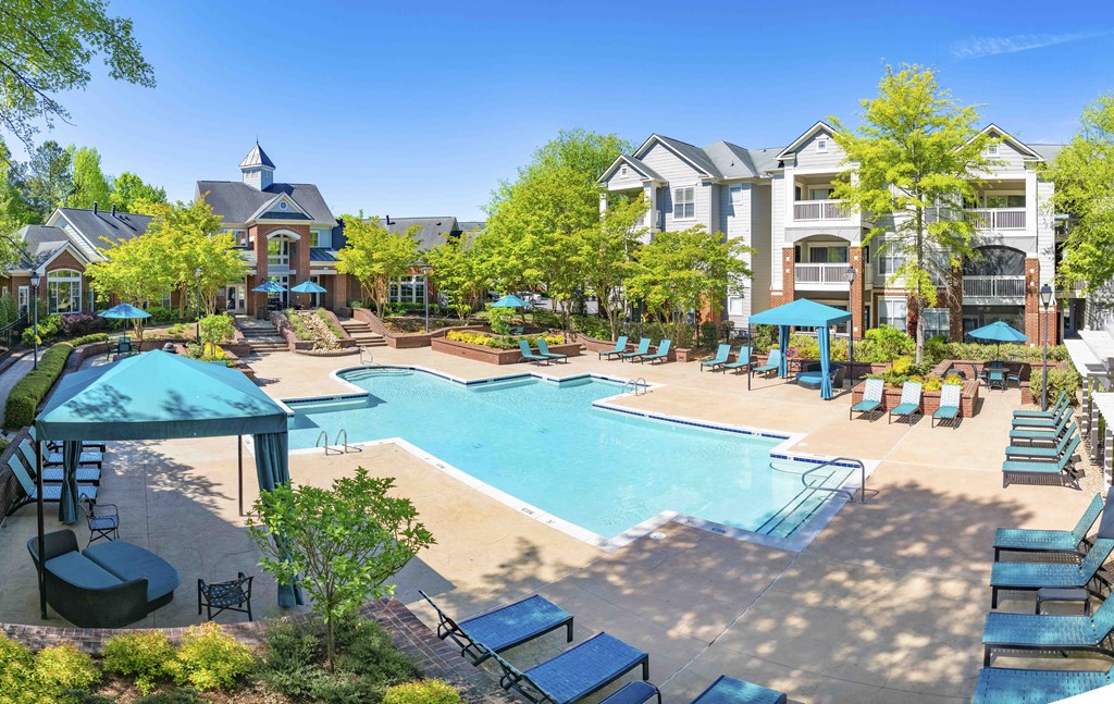 A large swimming pool surrounded by lounge chairs and umbrellas.