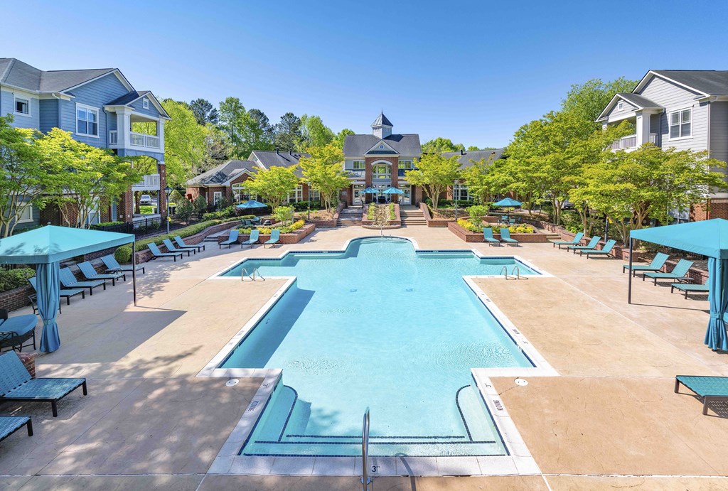 A large swimming pool surrounded by lounge chairs and umbrellas.