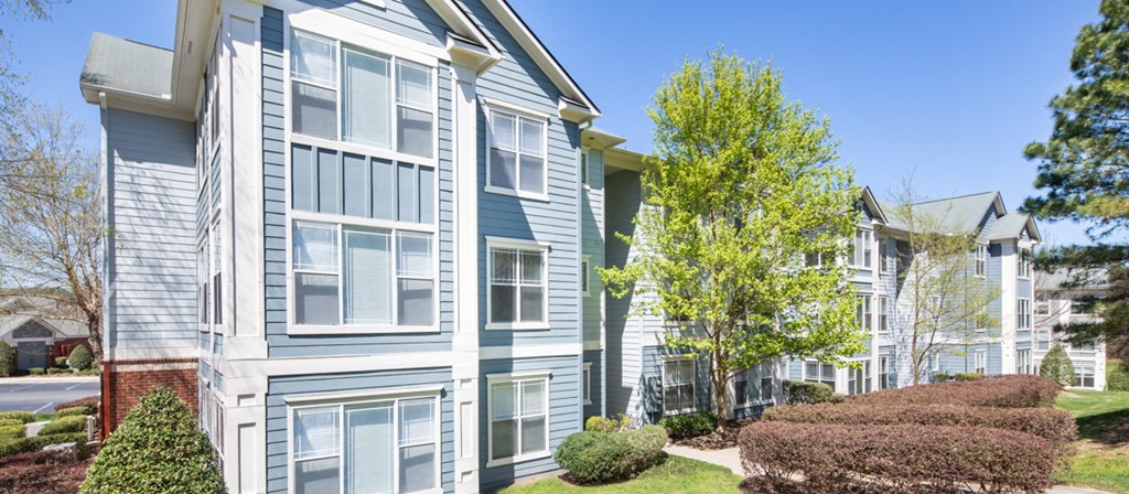 a blue and white apartment building with trees and a sidewalk