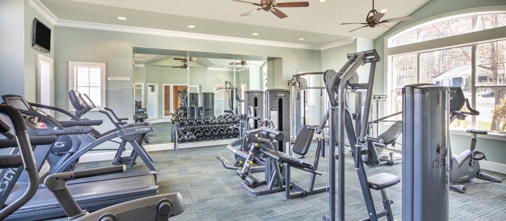 a gym with cardio equipment and a large window