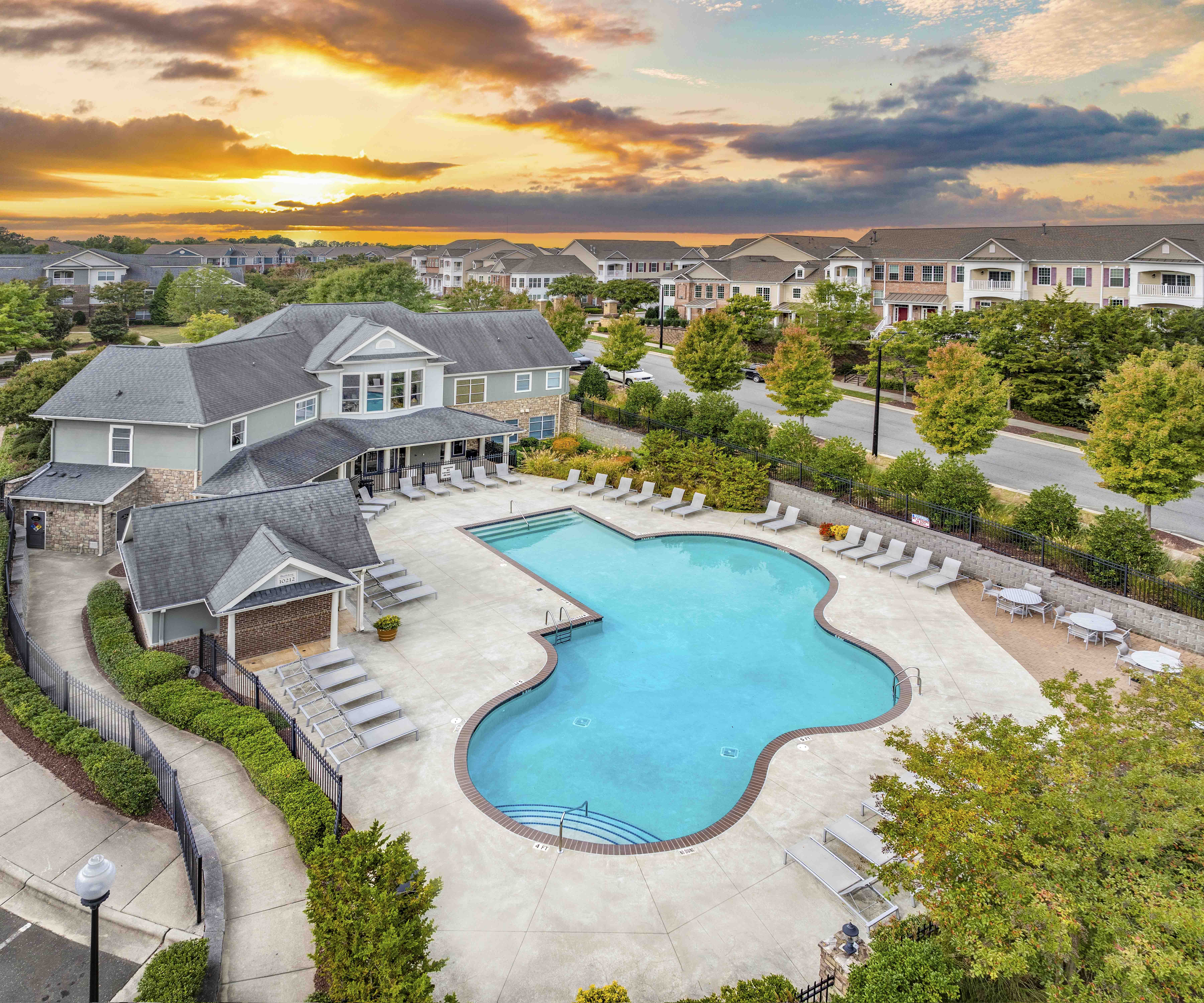 an aerial view of a swimming pool at sunset with houses