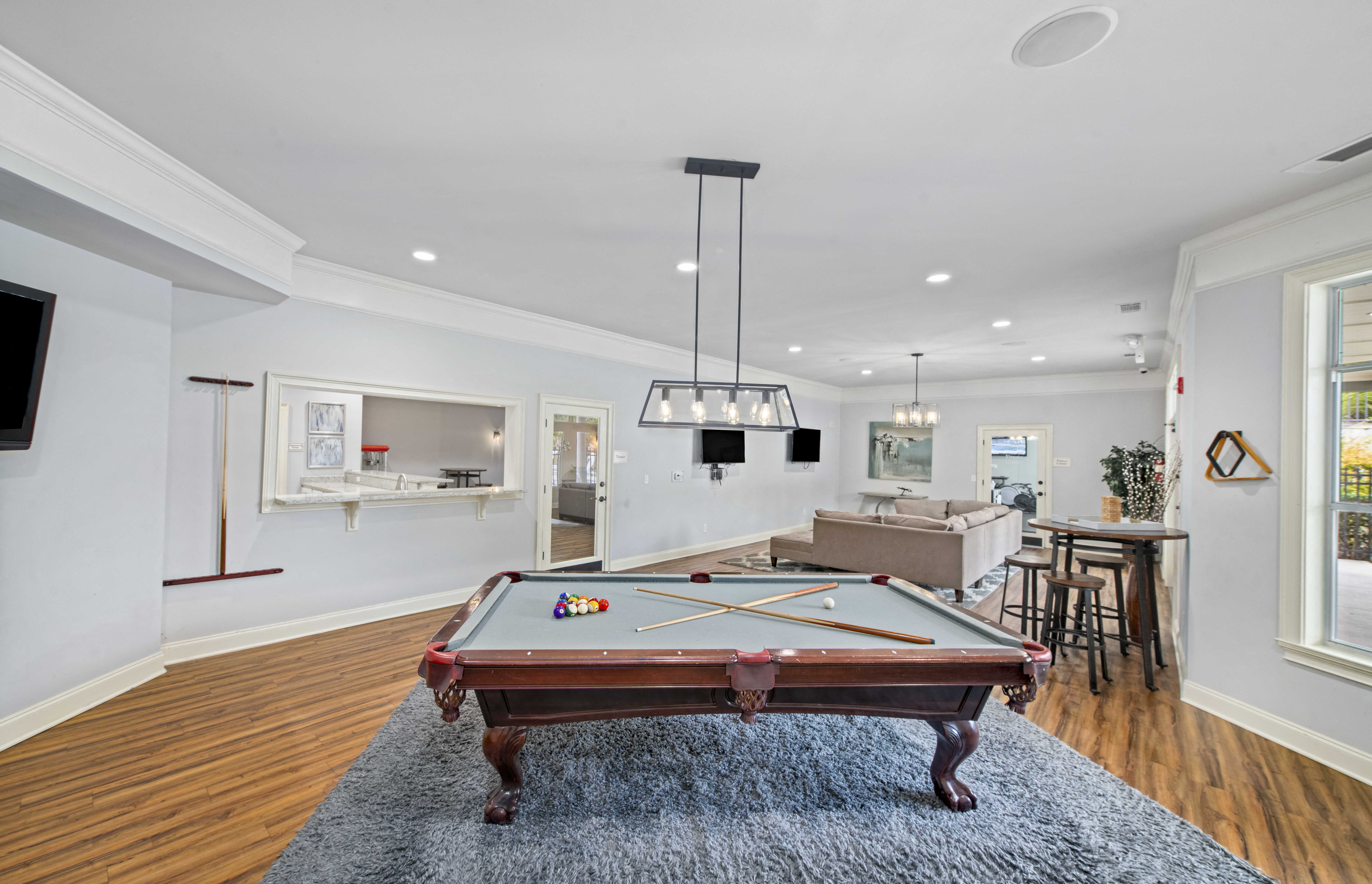 a pool table in a living room with a bar and a dining area